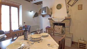 Un coin repas avec une table dressée pour deux personnes, une cheminée et un téléviseur fixé au mur.