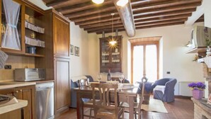 Une cuisine chaleureuse avec des meubles en bois, un lave-vaisselle en acier inoxydable et un coin repas comprenant des chaises et une table en bois.