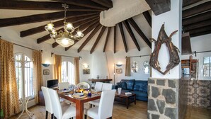 A spacious living area with a wooden dining table, white chairs, a blue sofa, and a stone accent wall. - Vista Ifach by Interhome (Calpe/Calp)