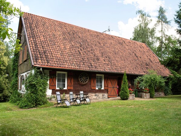 Une maison traditionnelle avec un toit en pente, des volets en bois et une grande fenêtre circulaire.
