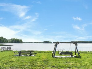 Un espace de pique-nique au bord du lac, équipé de bancs et d’une balançoire.