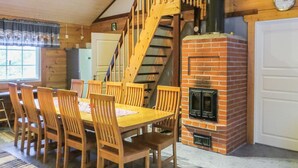 A dining area with a wooden table and chairs, a brick fireplace, and a wooden staircase. - Niementalo 2 by Interhome (Kinnula)