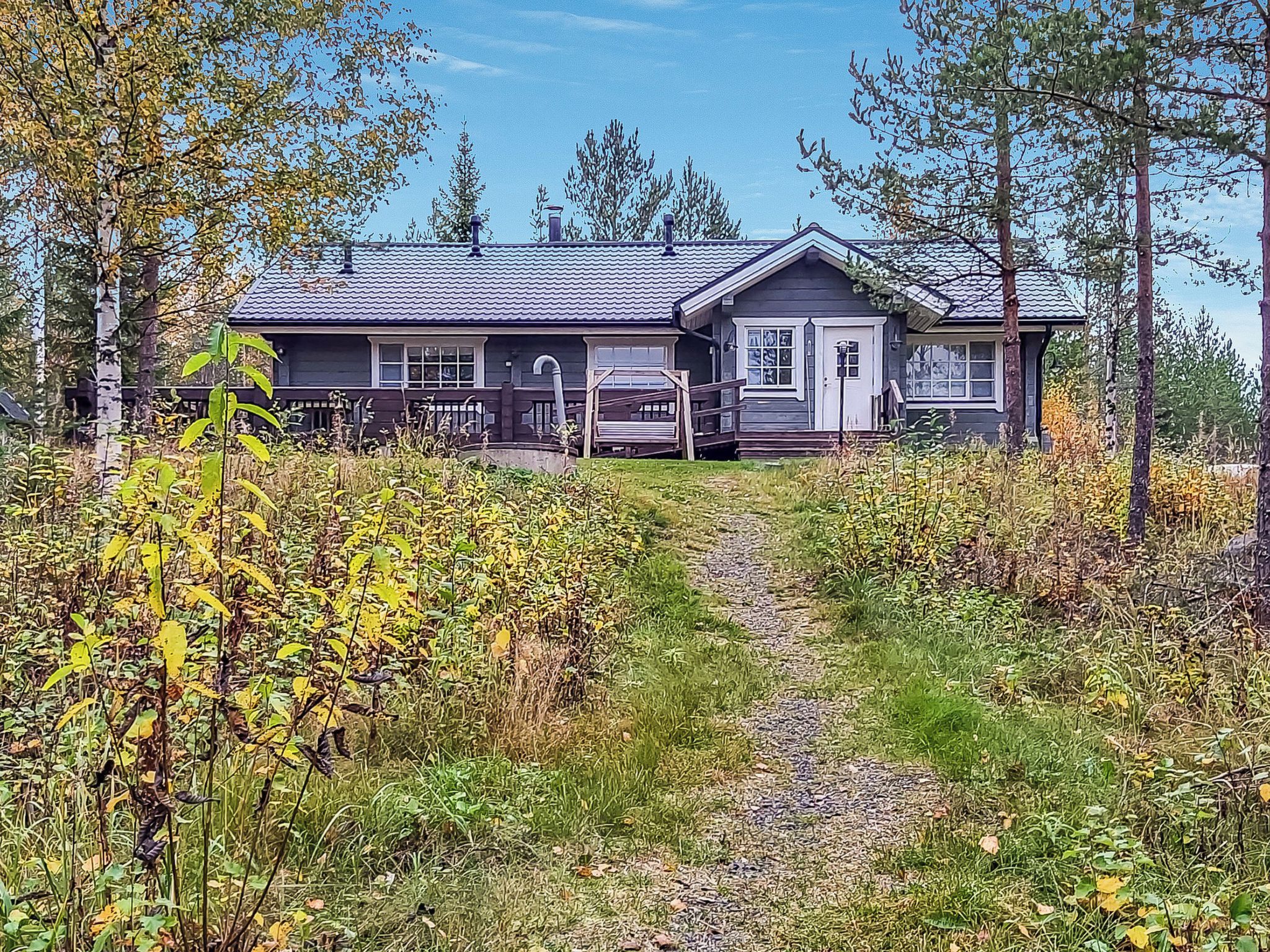 Une maison à deux étages avec un porche abrité et un chemin menant à l’entrée.