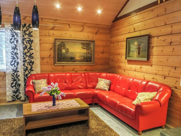 Un canapé en cuir rouge, une table basse en bois et deux tableaux encadrés accrochés au mur.
