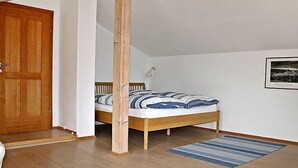 Un dormitorio con cama de madera, pared blanca y un cuadro enmarcado.
