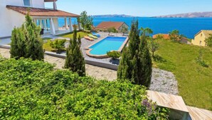 Ein Haus mit Swimmingpool, überdachter Terrasse und Meerblick.