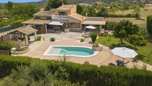 Una casa grande con piscina, patio y abundante vegetación.