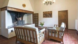 Ein gemütliches Zimmer mit Kamin, einer Chandelierleuchtre und zwei karierten Sesseln.