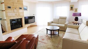 A modern living room with a flat-screen TV, leather sofas, a coffee table, and a patterned rug. - Villa Mustra by Interhome (Trogir/Okrug Donji)