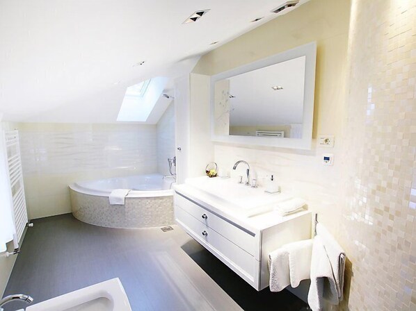 A modern bathroom with a freestanding bathtub, a vanity with a mirror, and a shower area.