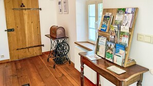 A room with a wooden door, a vintage sewing machine, and a bulletin board filled with pamphlets.