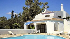 Ein Poolbereich mit Pool, Liegestühlen und einem Gebäude mit einem Ziegeldach.