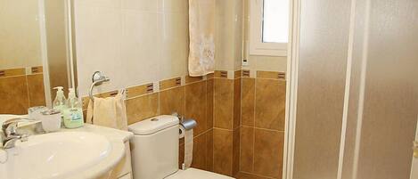 A bathroom with a toilet, sink, and shower.