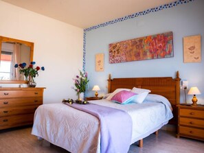 Una camera da letto con un letto in legno, comodini, una cassettiera, uno specchio e un quadro appeso al muro.