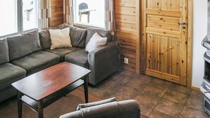 Un salon chaleureux avec un ensemble de canapés, une table basse et une porte en bois.