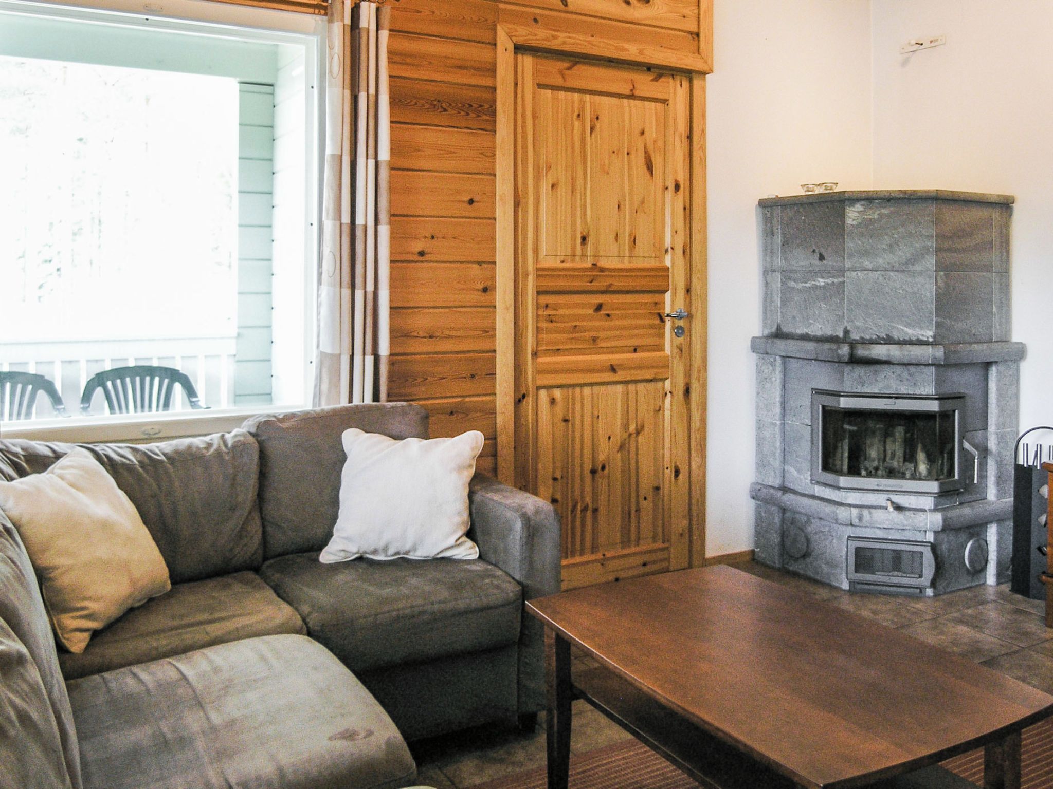 A cozy living room with a sofa, a table, a stone fireplace, and a wooden door.