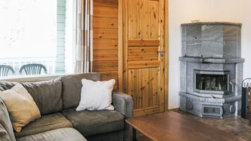 A cozy living room with a sofa, a table, a stone fireplace, and a wooden door.
