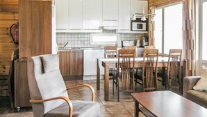 Une cuisine chaleureuse avec des meubles en bois, une table à manger avec des chaises et un réfrigérateur.