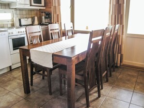 Una cocina con una mesa de comedor y sillas, un microondas y una cafetera.