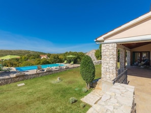A pool area with a stone wall, a grassy lawn, and a view of the surrounding landscape. - Vacation home Albina by Interhome (Rabac/Skitaca)