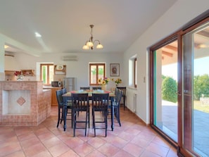 A dining area with a tiled floor, a central table with chairs, a chandelier, and a view through a glass door to an outdoor area. - Vacation home Albina by Interhome (Rabac/Skitaca)