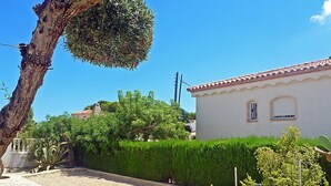A white building with a tiled roof, surrounded by well-maintained hedges and a tree. - Marinada by Interhome (L'Ampolla)