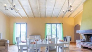 A dining area with a white table and chairs, a wooden ceiling, and a brick fireplace. - Les Vendanges by Interhome (Narbonne-Plage)