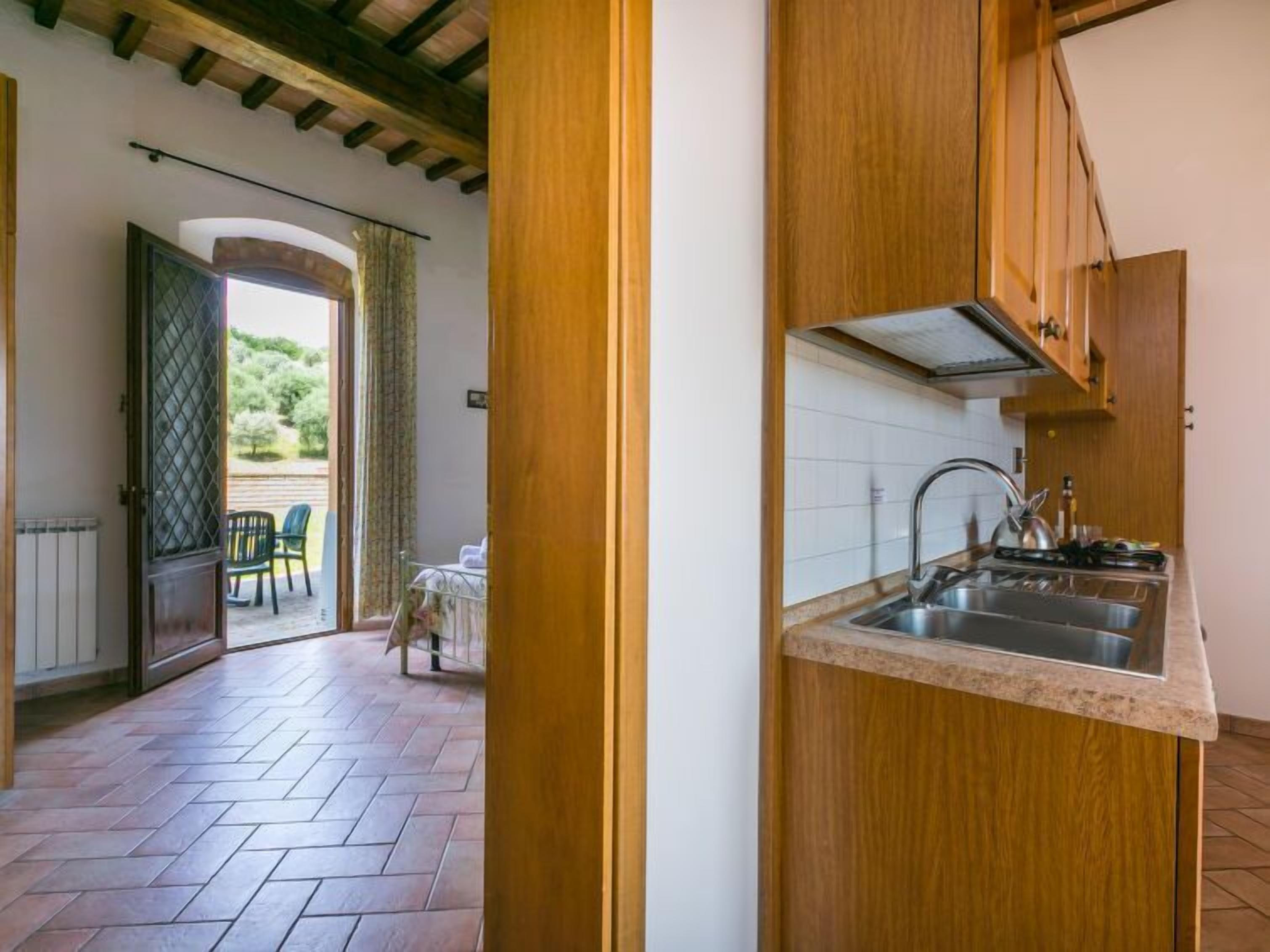 A kitchen with wooden cabinets, a stainless steel sink, and a tiled backsplash.