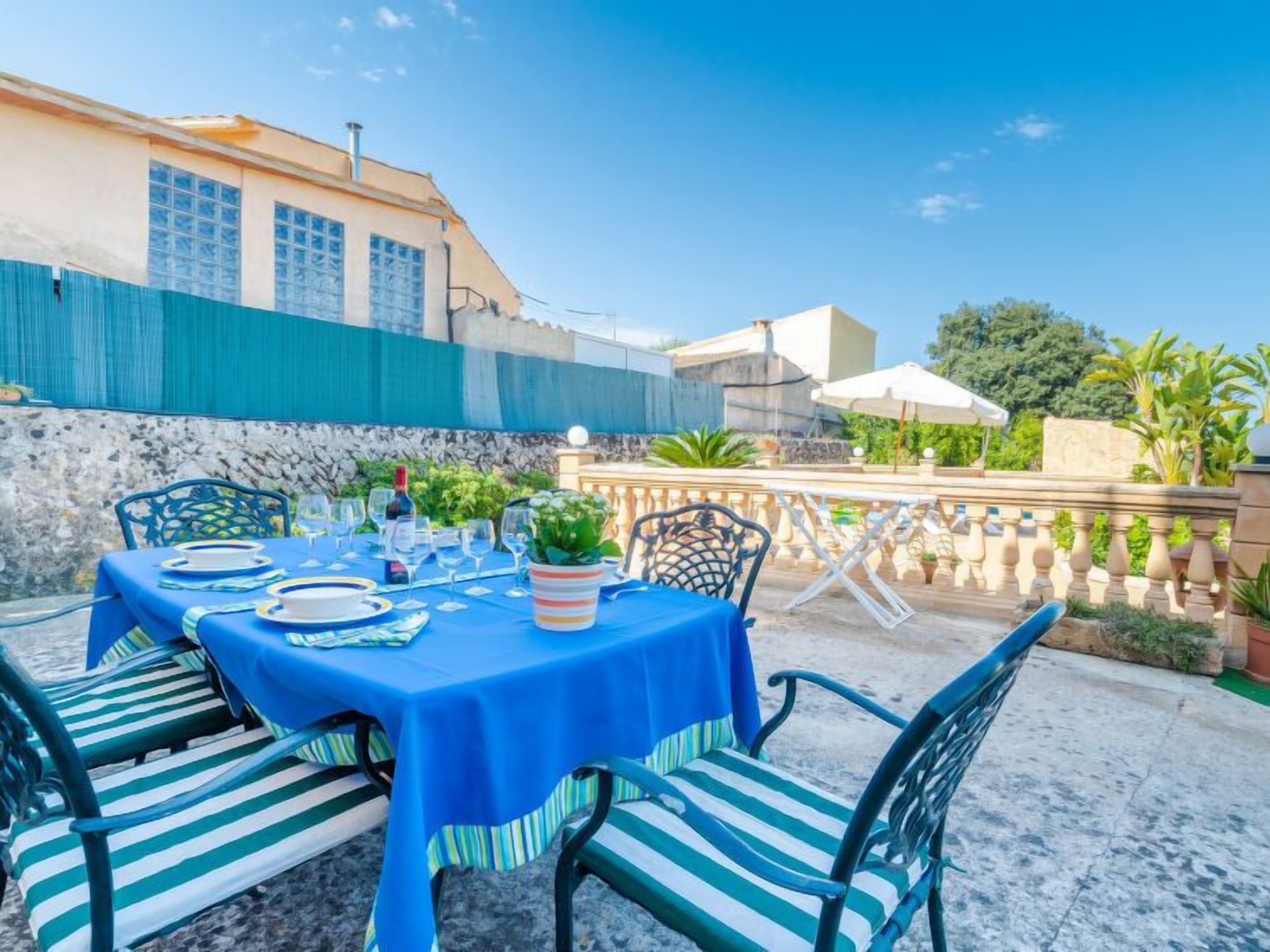 An outdoor dining area with a table set for four, surrounded by chairs with striped cushions.