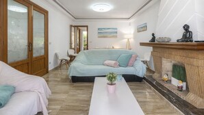 Ein Zimmer mit einem Bett, einem Sofa, einem Couchtisch, einem Kamin und einer Tür mit satinierten Glasscheiben.