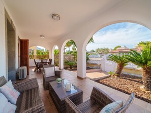 A covered outdoor patio with wicker furniture, a dining table, and a view of the surrounding area. - Villa Rosa by Interhome (Port d'Alcúdia)
