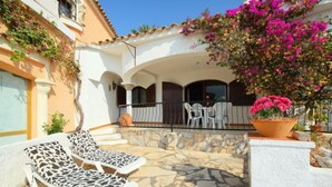 A patio with stone flooring, two lounge chairs, a table with chairs, and a potted plant with pink flowers. - Peces 3 by Interhome (Peñiscola)