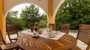 A round wooden table with four chairs, set under a wooden pergola with arches, surrounded by greenery. - Vacation home Maggie by Interhome (Rabac/Sveti Lovrec Labinski)