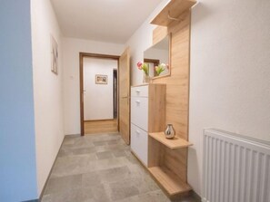 Stylish hallway with a door at the end, a cabinet, and a shelf with a vase.