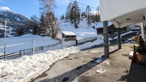 Un paysage enneigé avec un bâtiment au design moderne, une zone délimitée par une clôture et, au loin, une vue sur des montagnes.