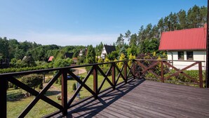 A wooden deck with a metal railing overlooking a residential area with houses and trees.