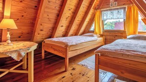 A cozy wooden cabin with two beds, a table, and a window with curtains.
