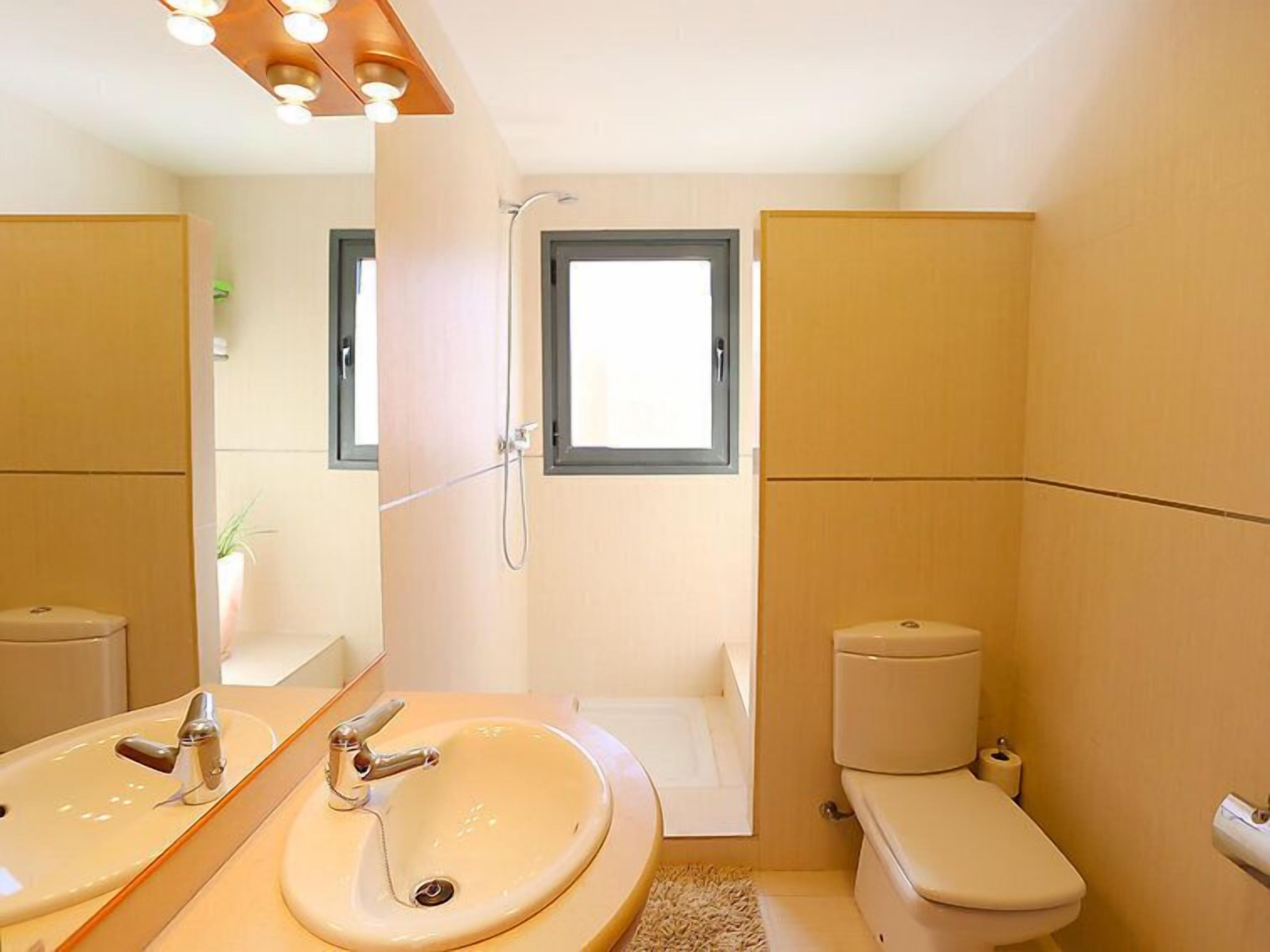 Une salle de bain moderne équipée d’un lavabo, d’un miroir, de toilettes et d’une douche.