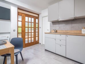 A modern kitchen with white cabinets, a wooden countertop, and a built-in stove.