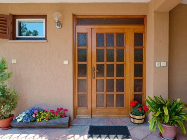 A wooden front door with a glass panel, a small window above it, and a potted plant to the left. - Apartment Beni by Interhome (Opatija/Pobri)