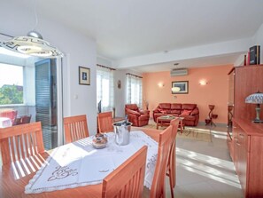 A dining area with a table set for four, a sofa, and a cabinet.