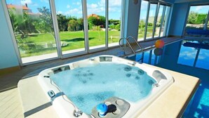 Ein Whirlpool mit Blick auf einen Pool und einen Garten.