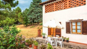 A patio with a table and chairs, surrounded by potted plants and a brick wall. - Tribolina by Interhome (Cavriglia)