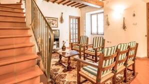 A spacious living room with a wooden staircase, a fireplace, and striped chairs. - Tribolina by Interhome (Cavriglia)