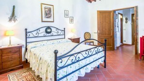 A bedroom with a bed, wooden nightstands, a patterned rug, and a ceiling with exposed beams. - Tribolina by Interhome (Cavriglia)