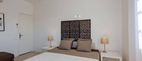 A bedroom with a large bed, two bedside tables, a decorative headboard, and a brown bench.