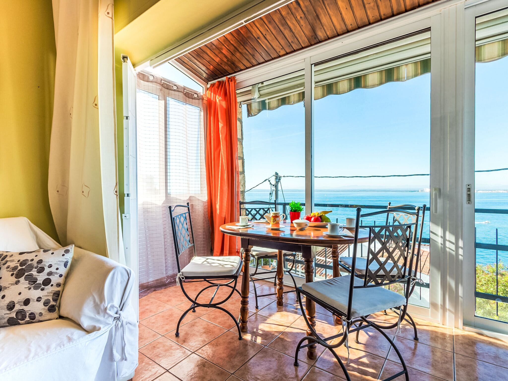 Ein Balkon mit Tisch für Zwei, Stühlen und Blick aufs Meer.
