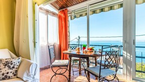 Ein Balkon mit Tisch für Zwei, Stühlen und Blick aufs Meer.