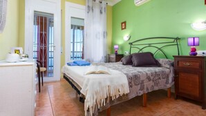Ein Schlafzimmer mit Bett, Nachttischen, einer Klimaanlage und Blick ins Freie.