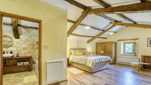 A bedroom with a large bed, wooden beams, a window, and a radiator. - Kapitani by Interhome (Hum)